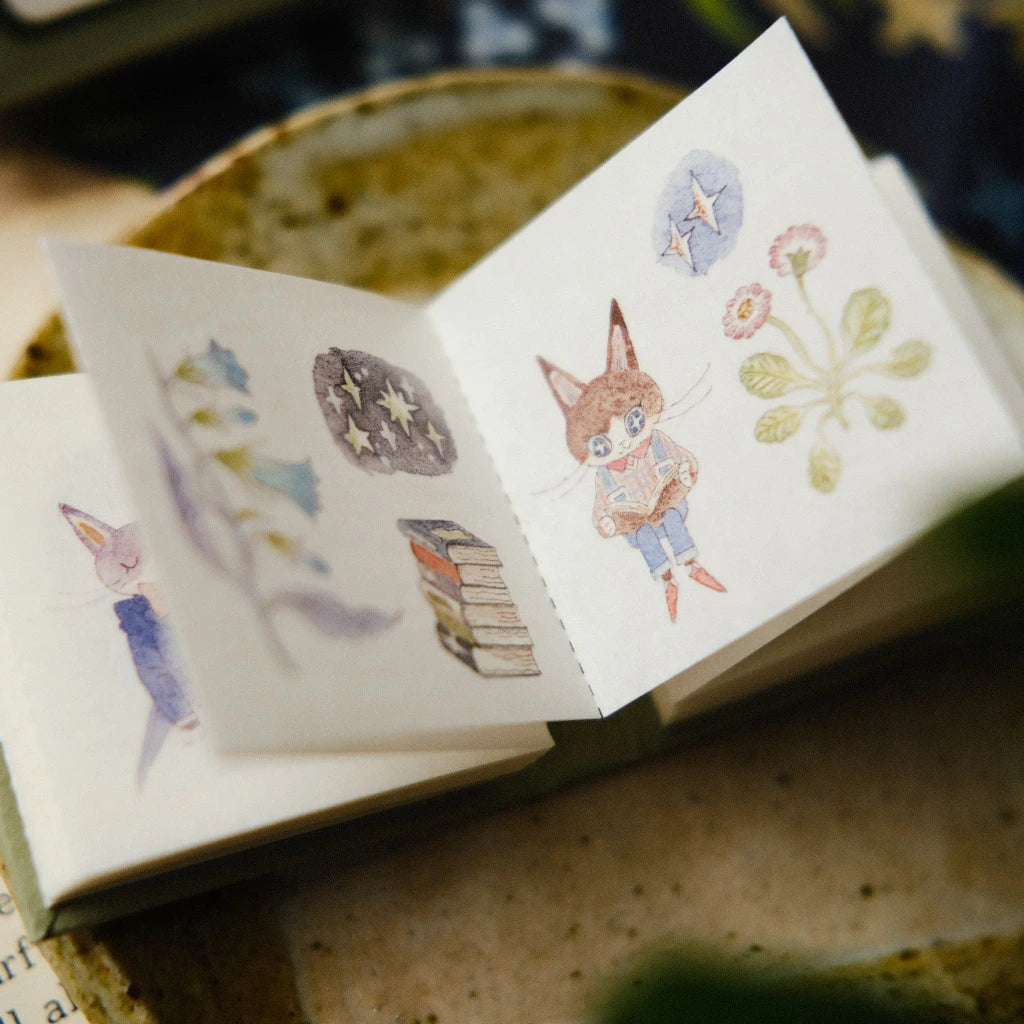 Small open book with illustrated stickers featuring a fox and nature elements.