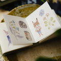 Small open book with illustrated stickers featuring a fox and nature elements.