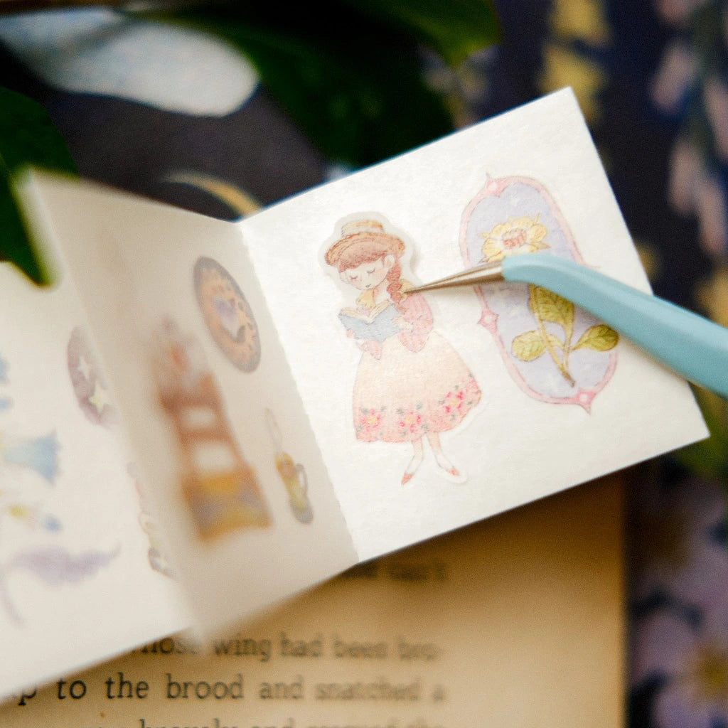 Illustrated book with a girl and butterfly design, held open by a pen.