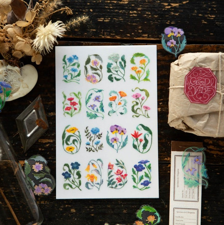 Sheet of floral stickers on a wooden surface with decorative items.