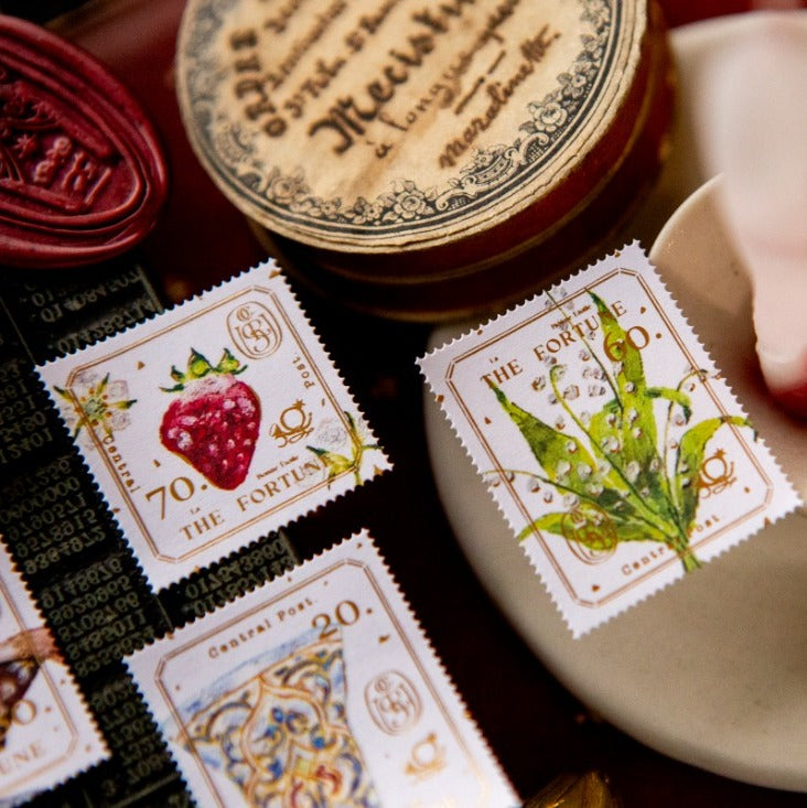 Decorative stamps with illustrations of a strawberry and a leaf, placed on a textured surface.