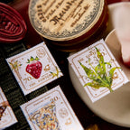 Decorative stamps with illustrations of a strawberry and a leaf, placed on a textured surface.