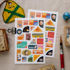 Sheet of colorful stickers on a textured surface with stationery items.