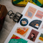 Sheet of stickers with various designs including an elephant, a cat, and text phrases, on a textured surface.