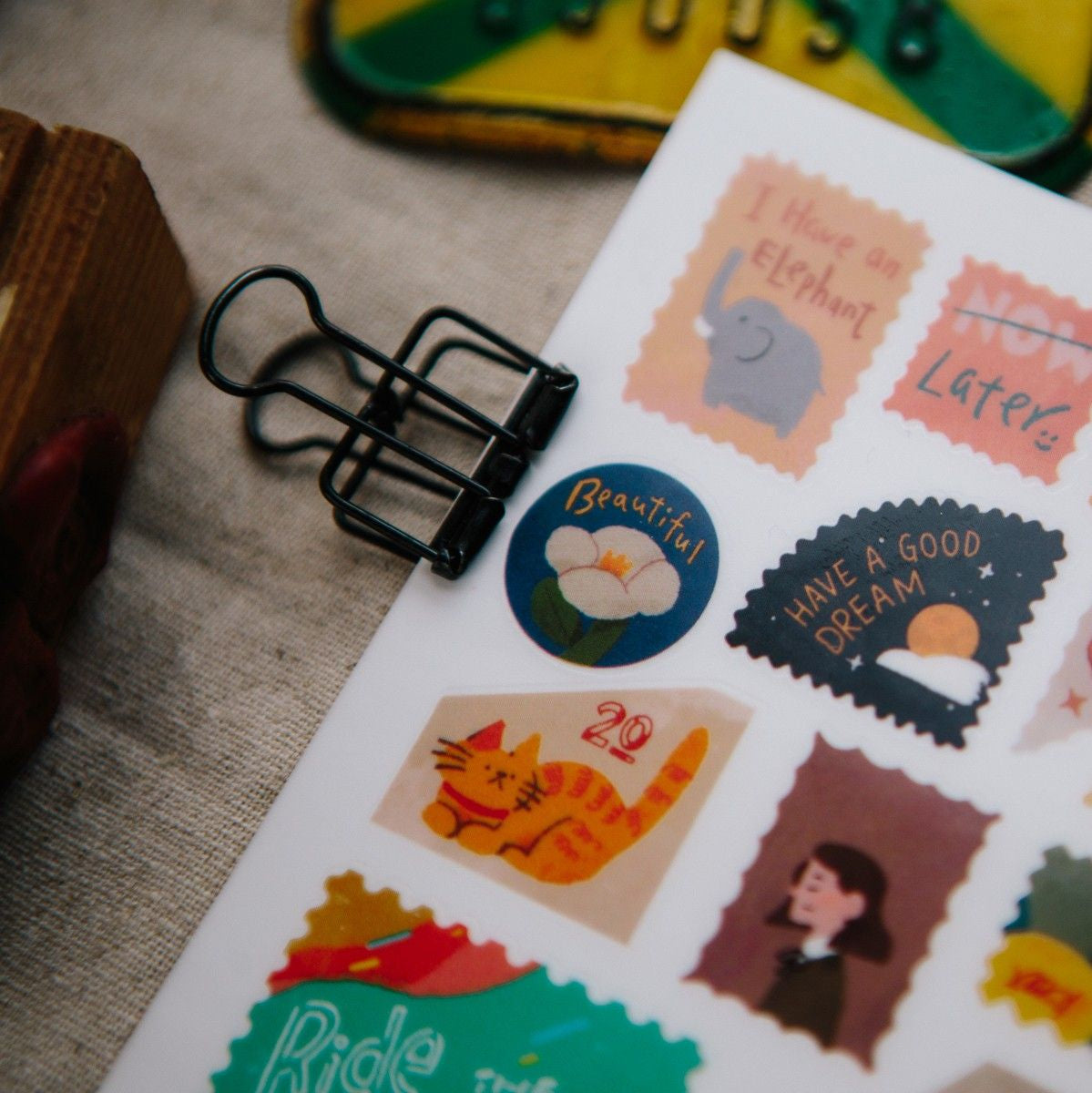 Sheet of stickers with various designs including an elephant, a cat, and text phrases, on a textured surface.