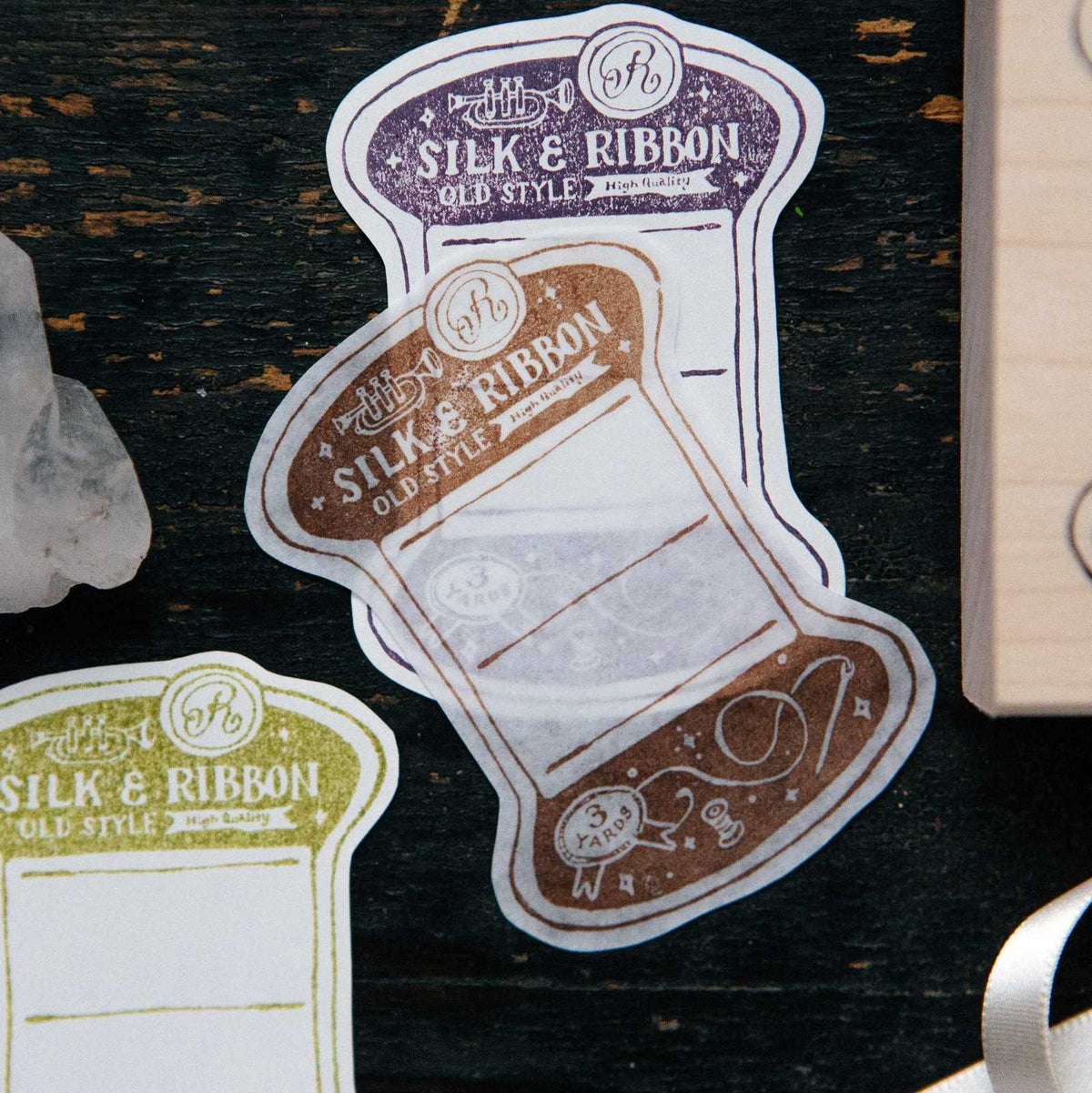 Thread Card Rubber Stamp spool impression of silk and ribbon on a dark wooden surface