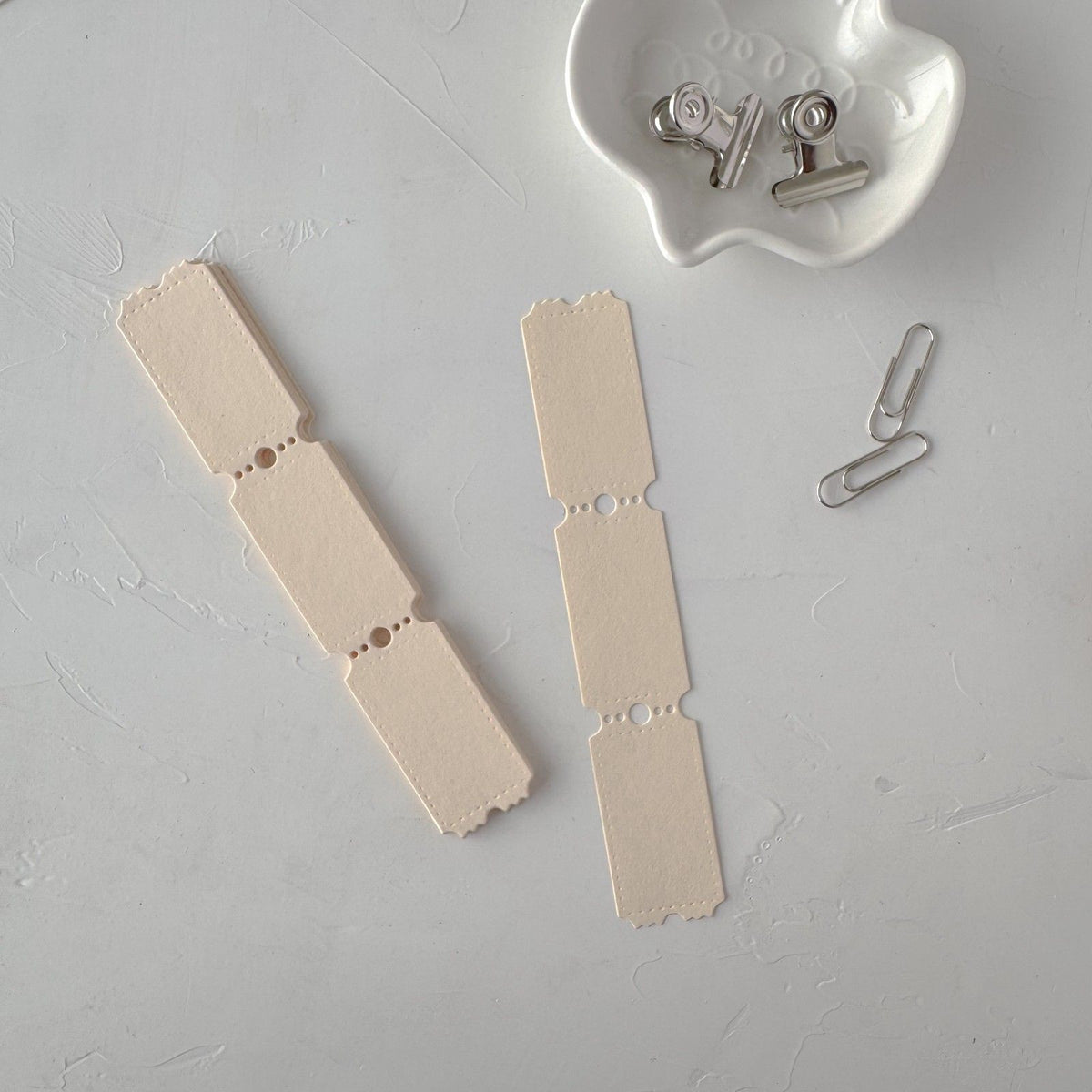 Cream Ticket Card Vol. 1 ephemera cards on grey with a white dish of small metal clips