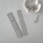 Metal dog tags and a paperclip on a textured gray surface