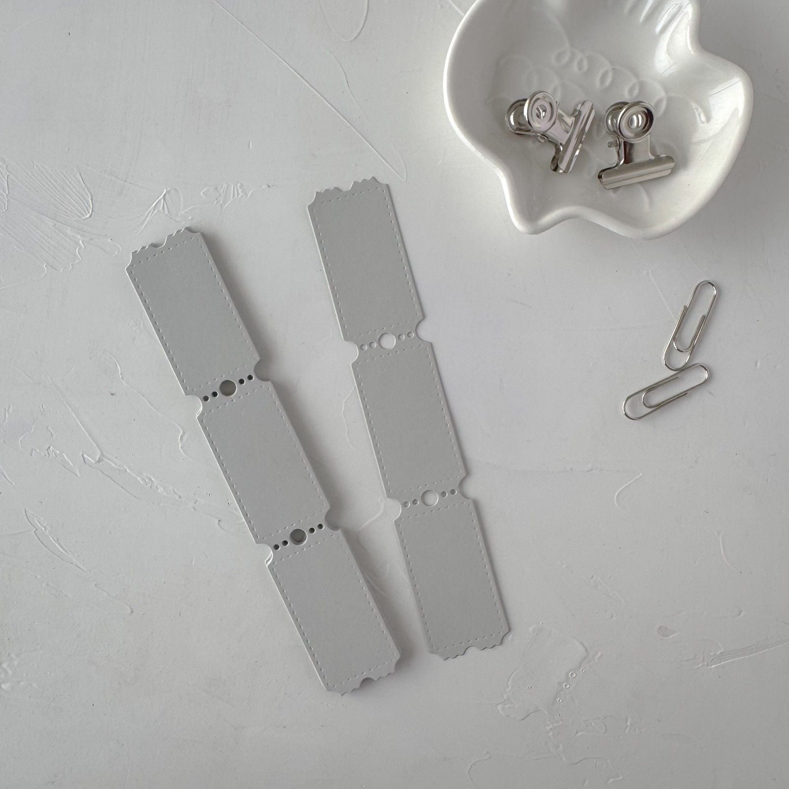 Metal dog tags and a paperclip on a textured gray surface