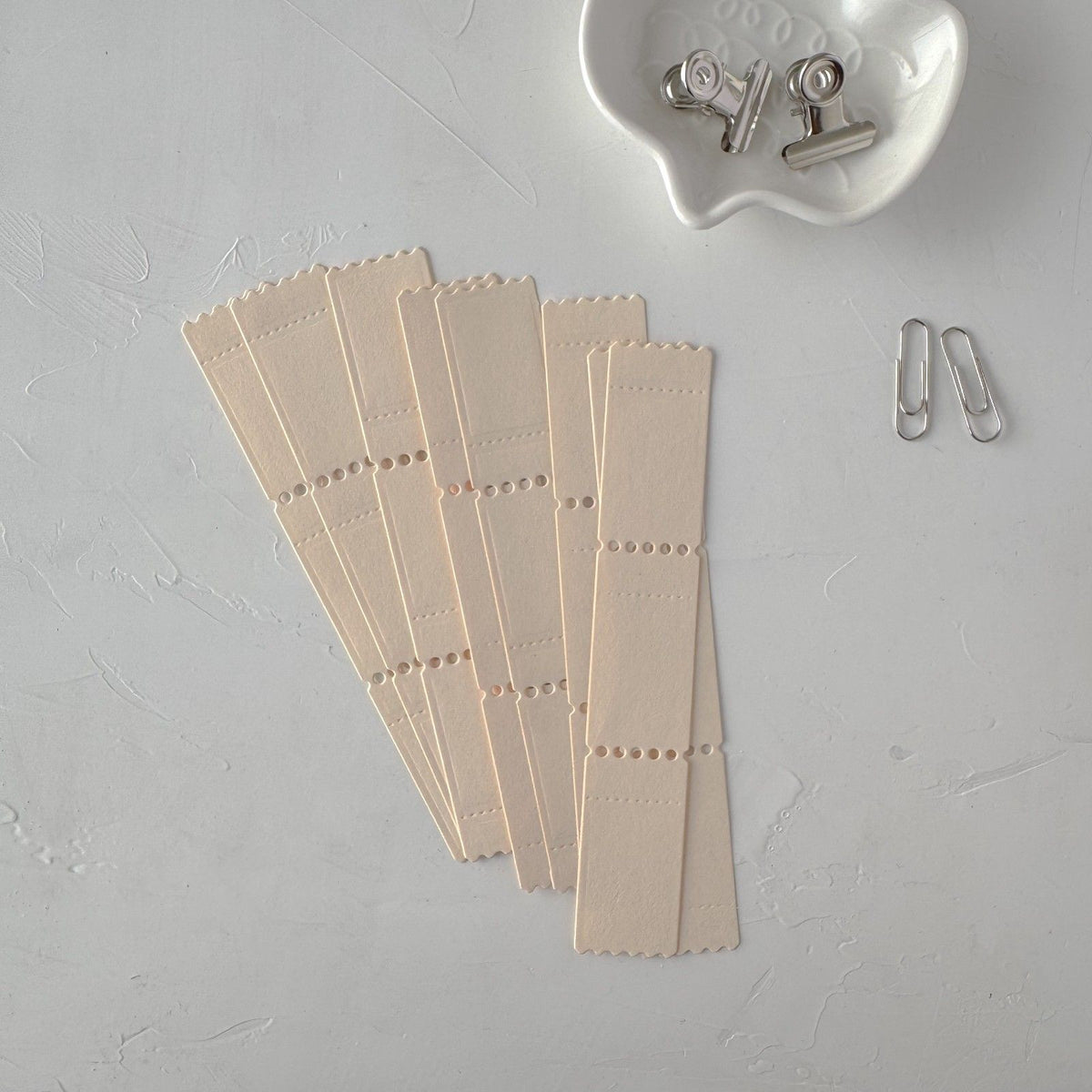 Cream Ticket Card Vol. 2 strips styled together with small clips on a grey surface