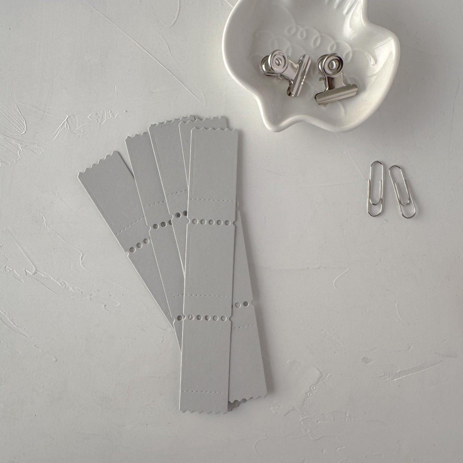 Full set of grey Ticket Card Vol. 2 strips with clips on a light grey surface, styled detail view