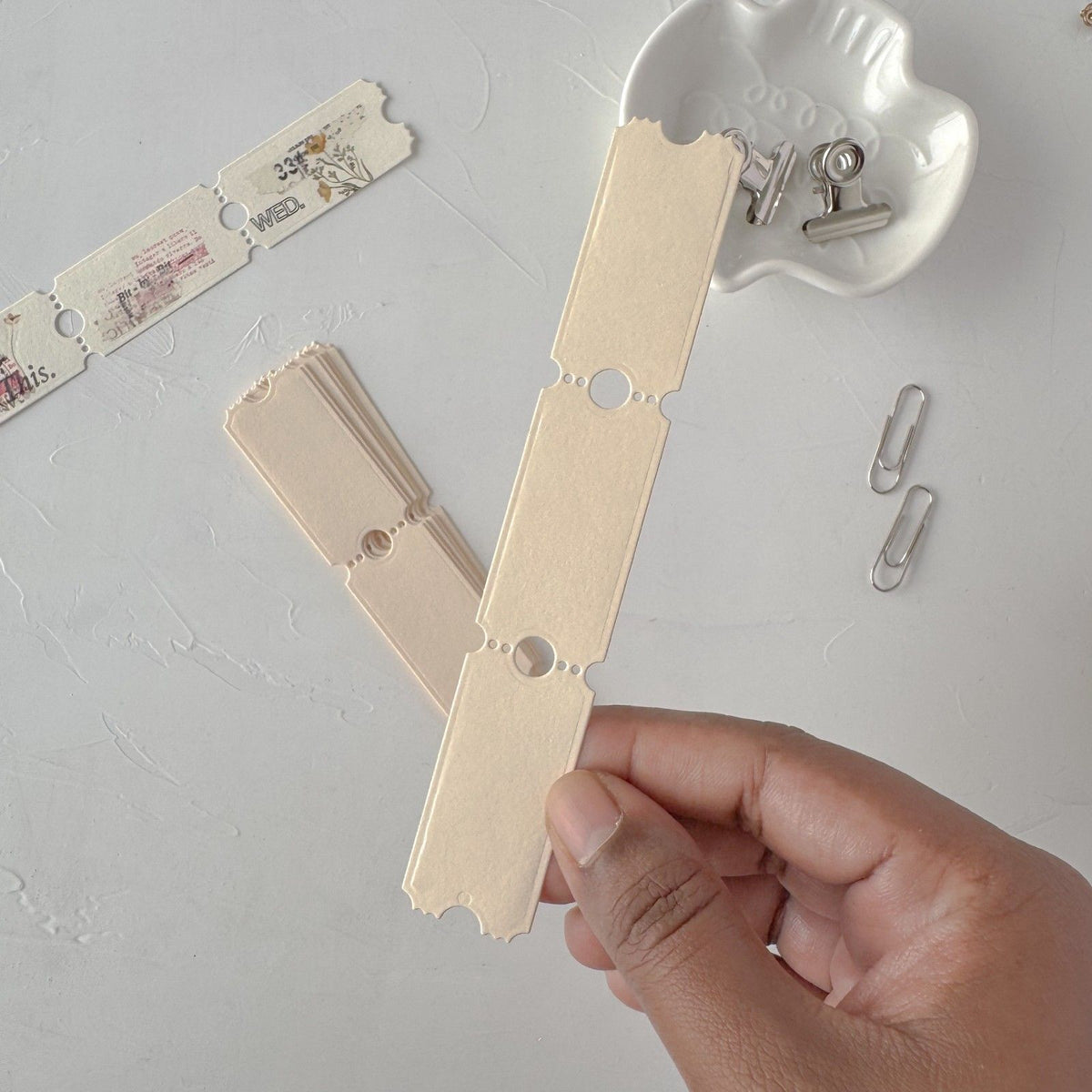 Cream Ticket Card Vol. 3 strips on a wooden clothespin held against light grey, styled detail view