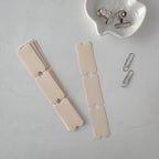 Metallic clip and two metal clips on a gray surface