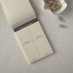Notebook with a time management layout on a light gray surface with paper clips.