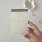 Hand holding a time management notebook with decorative paper clips on a light gray background