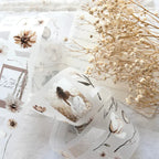 Decorative glass with floral design on a marble surface with dried flowers.