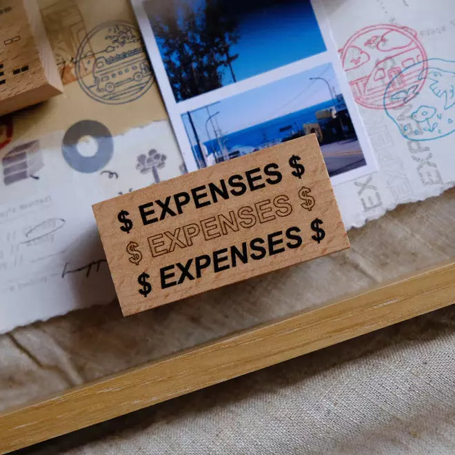 Travel Journaling Series Expenses stamp block on a surface with photos and stamped prints