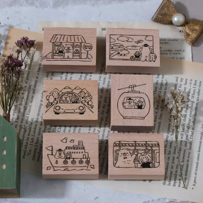 Flat lay of Travel Together rubber stamps showing bear and girl travel-themed illustrations on a book page backdrop