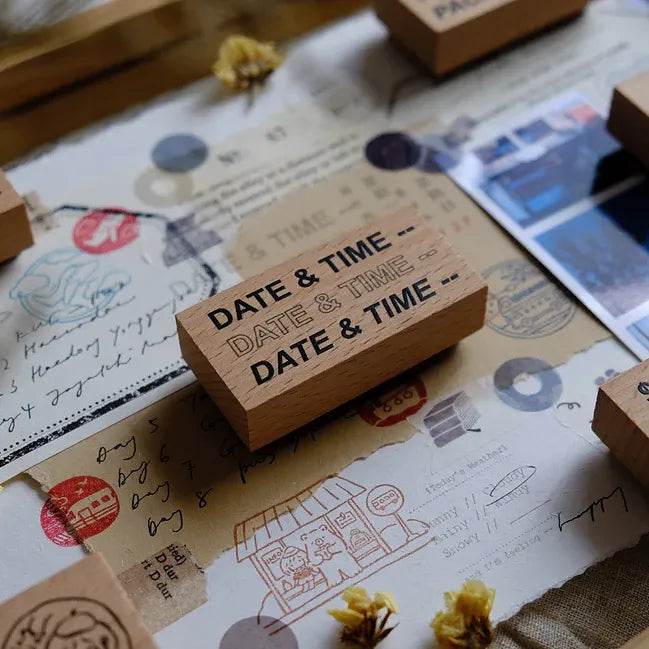 Wooden stamp with 'DATE & TIME' text on a textured surface with stamps and papers.