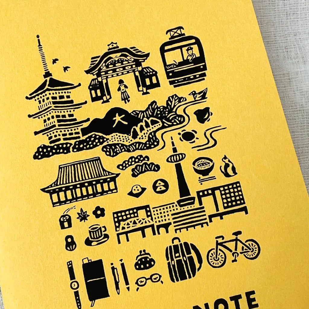 Yellow notebook cover with black travel-themed illustrations on a textured surface