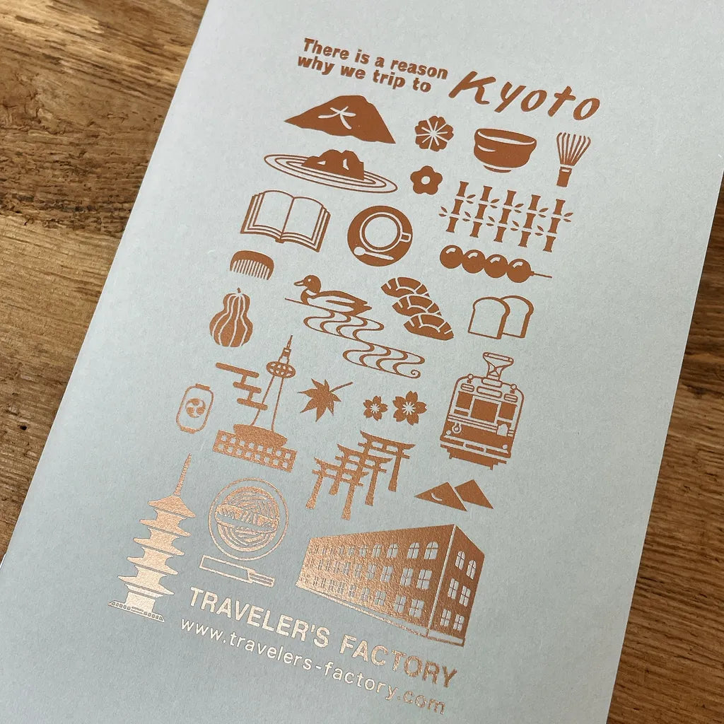 Notebook with Kyoto-themed illustrations and text on a wooden surface