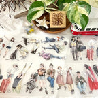 Matte PET tape with aesthetic traveler character illustrations displayed on a white surface with green plant leaves, wooden stamp, toy airplane, and miniature van for a cozy journaling setup.