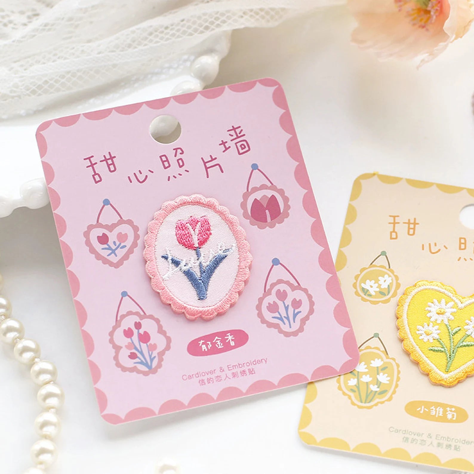 Floral embroidered patch on a pink card with Chinese text, set against a soft white background.