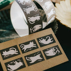 Cat-themed washi tape with a roll and samples on a cardboard sheet.