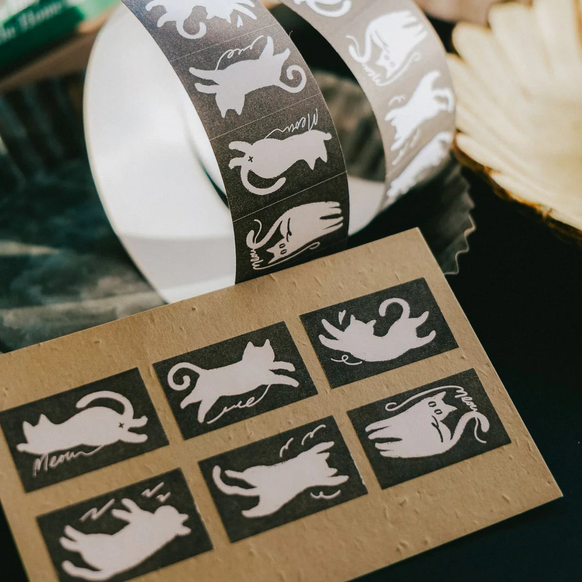 Cat-themed washi tape with a roll and samples on a cardboard sheet.