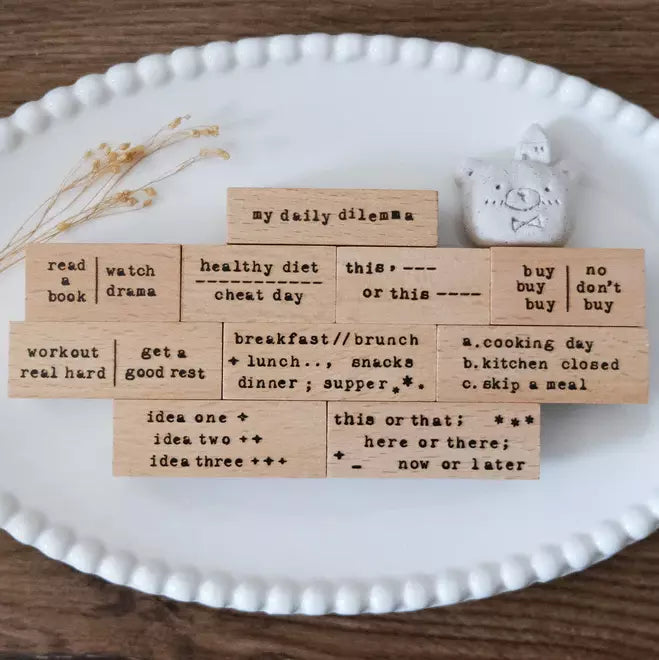 Typewriter Phrases My Daily Dilemma stamp set arranged on a white plate on a wooden backdrop