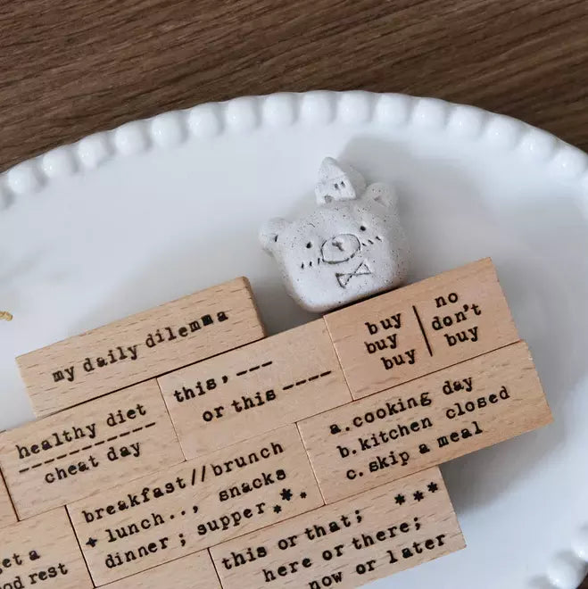 Typewriter Phrases wooden stamp blocks on a white plate beside a small plush toy