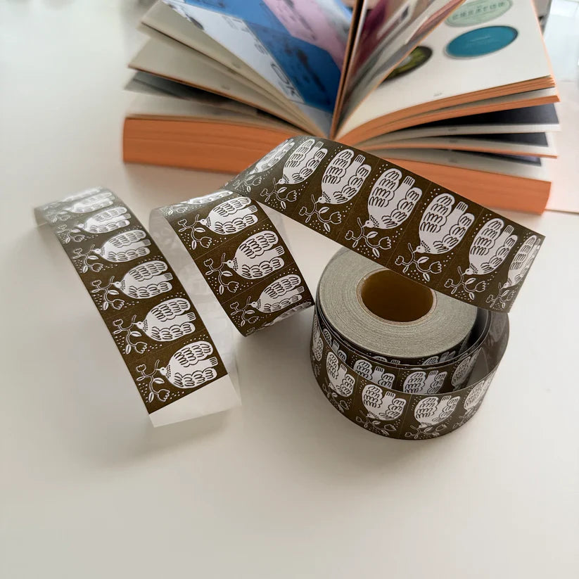 Decorative tape with hand designs on a white surface with books in the background