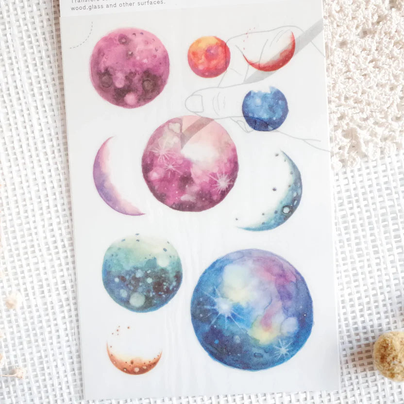 Sheet of planet-themed stickers with colorful designs on a textured surface.