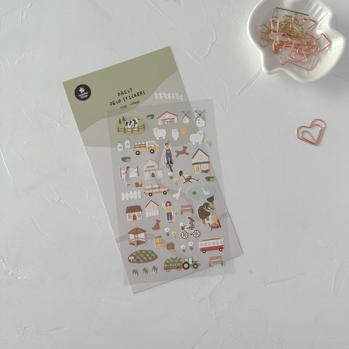 Decorative stickers on a white surface with paper clips, from the Village Sticker Sheet