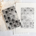 Two black and white patterned tiles on a textured surface