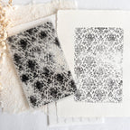 Two black and white patterned tiles on a textured surface
