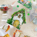 Decorative house-shaped stickers with greenery and a yellow door on a textured surface.