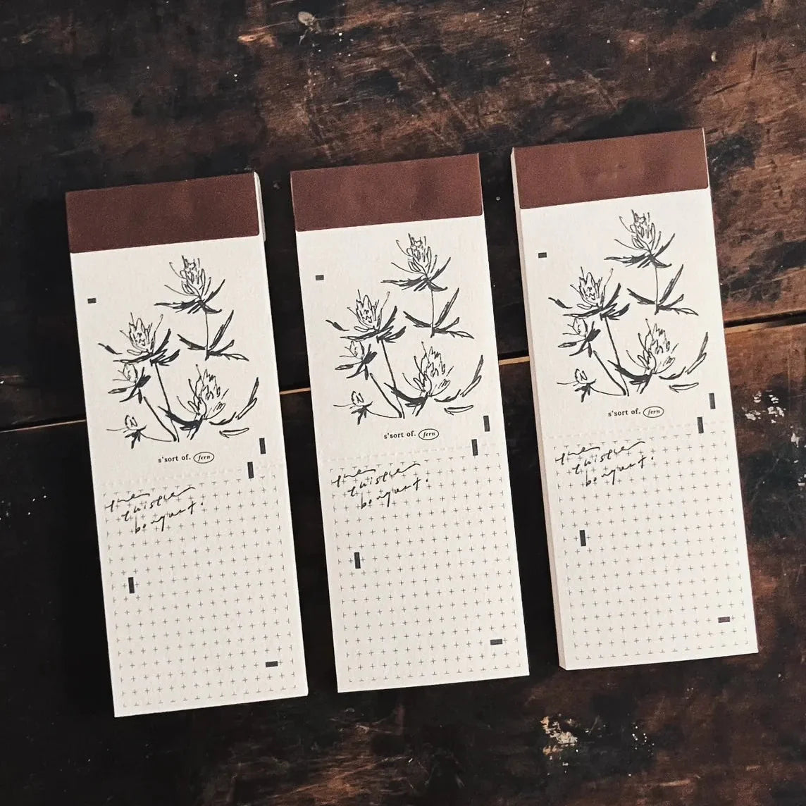 Three Vintage Hand-Torn Bouquet Memo Pads with thistle illustrations on a wooden surface
