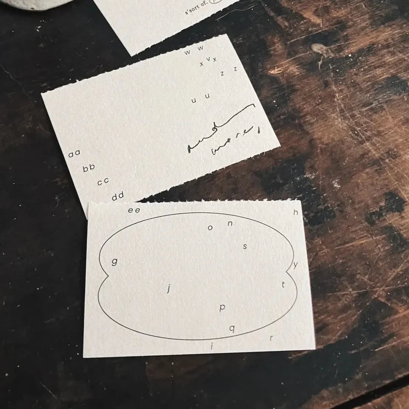 Two Vintage Hand-Torn Alphabets Memo Pad sheets with scattered letters on a wooden surface