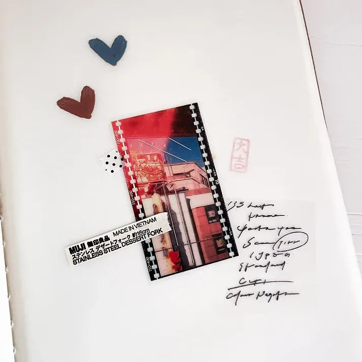 Small notebook with colorful design on a white surface with decorative hearts.