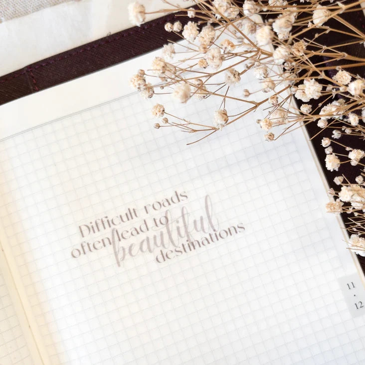 Beautiful Destinations Vinyl Sticker quote styled on an open book with dried flowers