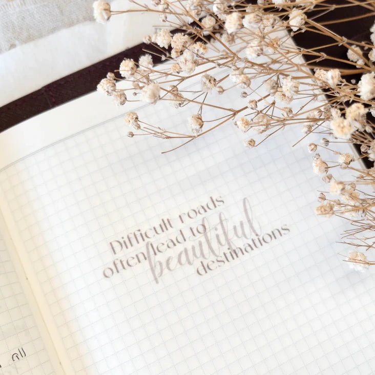 Beautiful Destinations Vinyl Sticker displayed on an open book page with dried florals