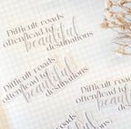 Motivational quote stickers on a white background with dried flowers.