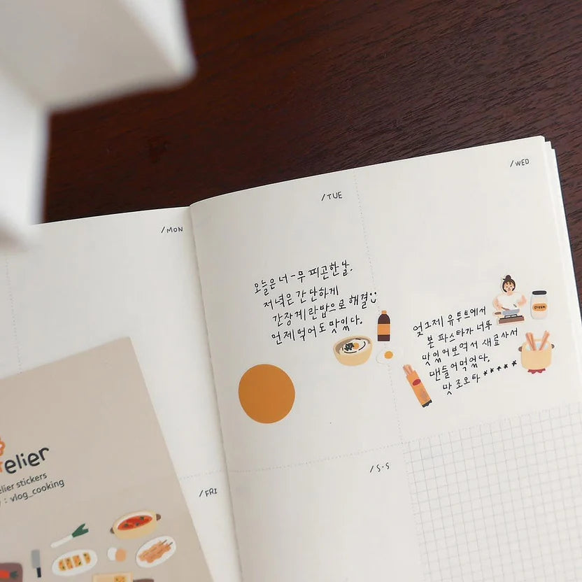 Open book with text and illustrations on a wooden surface, from the Vlog Cooking Sticker Sheet