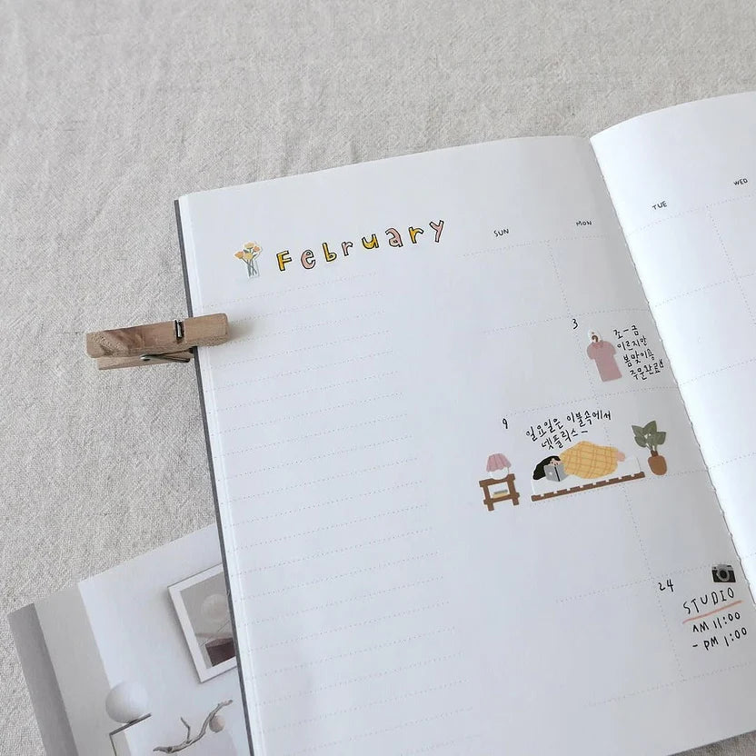 Open notebook with stickers on a light grey surface, from the Vlog Home Sticker Sheet