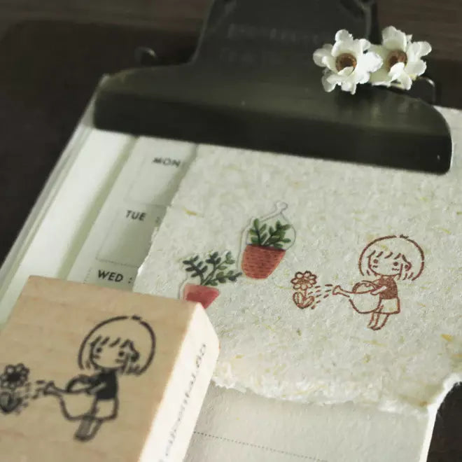 Mini Girls Watering Flower stamp showing a girl watering plants, printed on a white surface