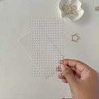 Hand holding a sheet of clear stickers with a white background