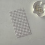 Sheet of small round stickers on a textured gray surface with a white object featuring a cactus design.