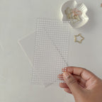 Hand holding a sheet of clear decorative stickers with a plain background