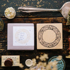 Wooden stamp with decorative design on a rustic wooden surface with other stamps and items.